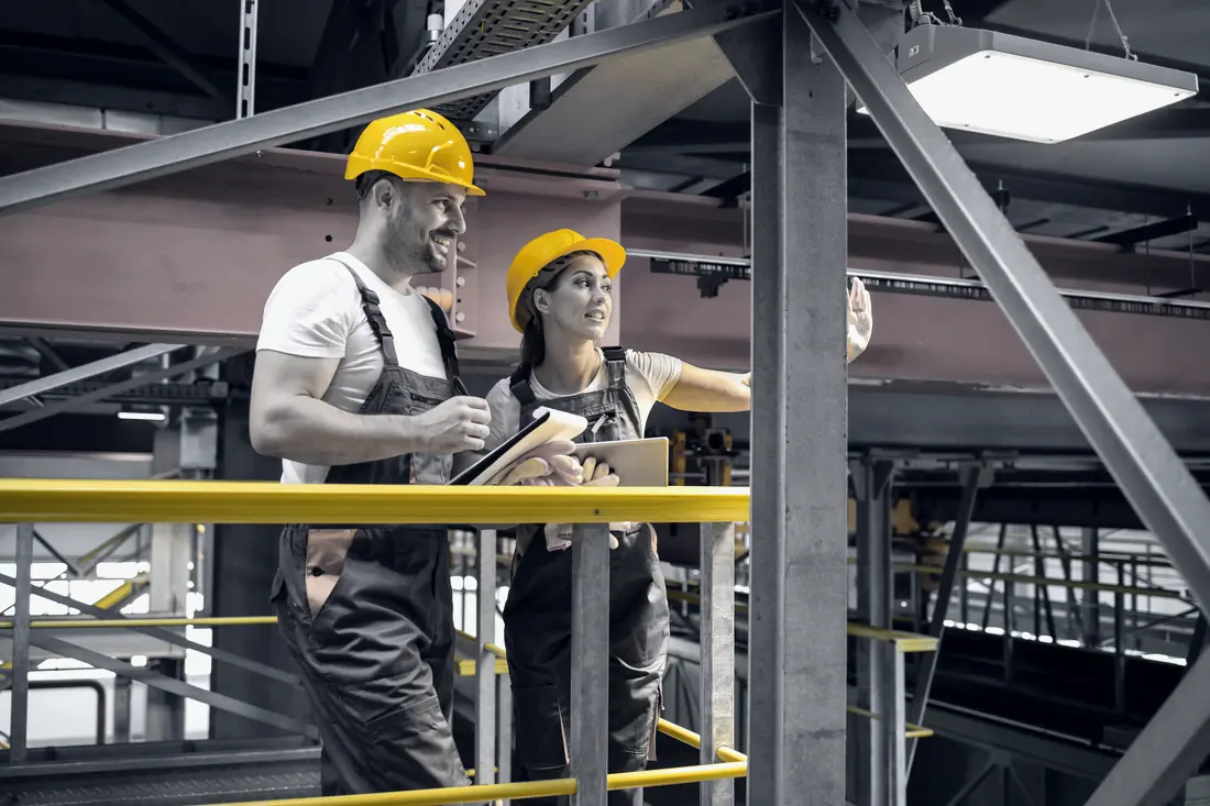 Ingenieros con equipo de protección revisando ideas en la nave de producción
