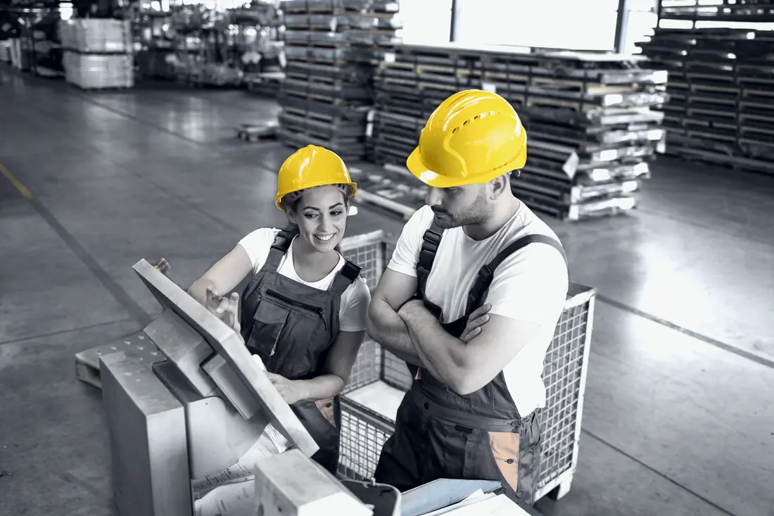 Empleados con casco amarillo operando máquinas en la línea de producción